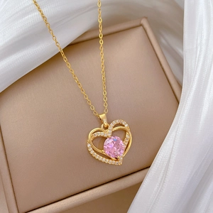 Détail du collier coeur rose serti de zircons posé sur un coffret à bijoux beige