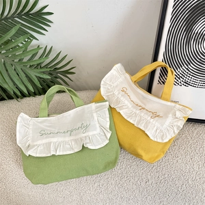 Detail of canvas tote bags with ruffle edges and Summerparty embroidery in green and yellow