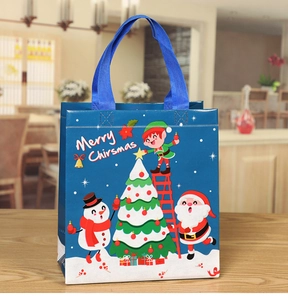 Blue Christmas non-woven gift bag featuring Santa and snowman prints on wooden table
