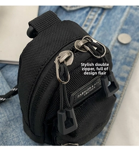 Close-up of black nylon mini crossbody bag featuring dual metal zippers and fashion label