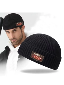 Detail of black ribbed knit beanie featuring a vintage sport leather patch and rivets