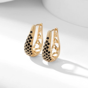 Detail of gold U-shaped hoop earrings with black pavé stones and hollow heart cutouts