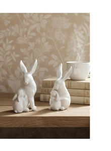 Détail de figurines de lapins en résine blanche sur table en bois avec livres et café