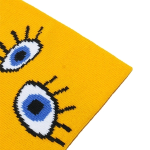 Detail of yellow knit beanie featuring an embroidered cartoon eye with blue iris design
