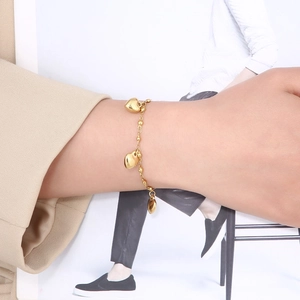 Detail shot of a minimalist gold heart pendant bracelet worn on a woman's wrist