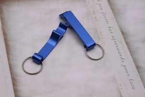 Close-up of two blue metal keychain bottle openers on a rustic textured fabric background