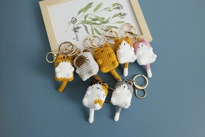 Group of seven handmade crochet cat keychains in various colors on a blue background