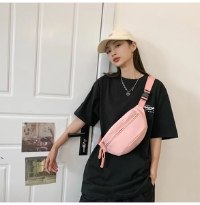 Detailed view of a pink canvas crossbody bag with adjustable strap and plastic buckle