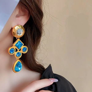 Detailed view of vintage gold earrings with blue gemstones and diamonds on model