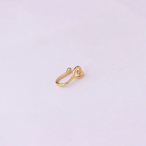 Close-up of golden heart-shaped faux nose ring with inlaid zircon on white background