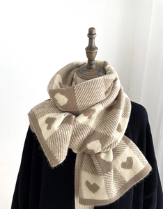 Detailed view of the chunky knit pattern and heart jacquard on this brown winter scarf