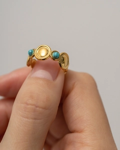 Detail of bohemian gold ring featuring two round turquoise stones on a wavy band