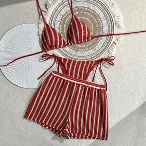 Detailed view of red and white striped three-piece bikini set with textured knit fabric