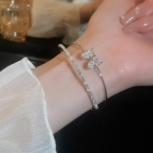 Detailed view of silver bow and rhinestone double layer cuff bracelet on wrist