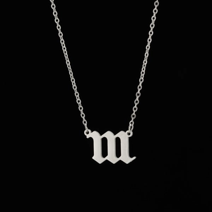 Gros plan du pendentif lettre M en argent gothique avec une fine chaîne à maillons