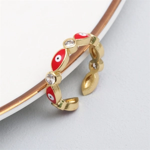 Macro detail of gold-plated evil eye ring with white zircons on a white ceramic plate