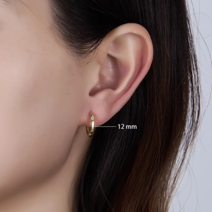 Close-up of 12mm polished gold sterling silver hoop earring worn by a female model
