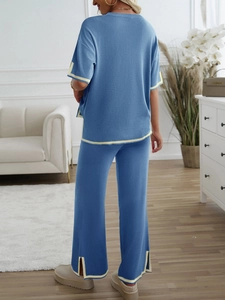 Rear view of blue knit set with contrast yellow trim and side slits on wide-leg pants