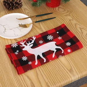 Détail d'une serviette de Noël à carreaux rouges et noirs avec motifs rennes et flocons