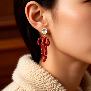 Close-up of red enamel bow earrings with square zircon and gold star patterns