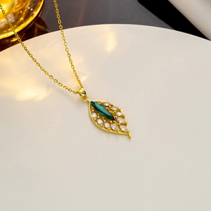 Close-up of a gold leaf pendant with a large green gemstone and zircon accents