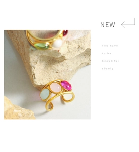 Detail view of gold adjustable ring with three colorful oval gems on natural rock background