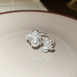 Detail of silver open ring with white pearls and sparkling zircons on ceramic tray