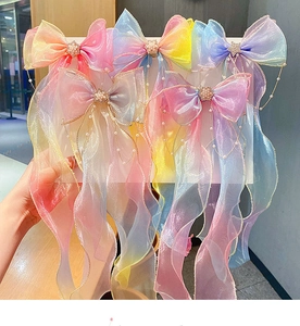 Close-up of rainbow gradient mesh bow hair clips with pearls and long wavy ribbons