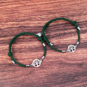 Detail of tree of life charm and heart magnetic clasp on dark green woven bracelets