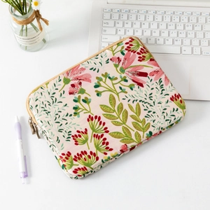 Detail of floral embroidery on a pink quilted laptop sleeve with a metal zipper