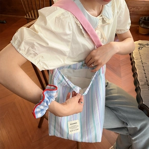 Détail du sac cabas en toile rayée montrant le bouton pression et l'étiquette tissée