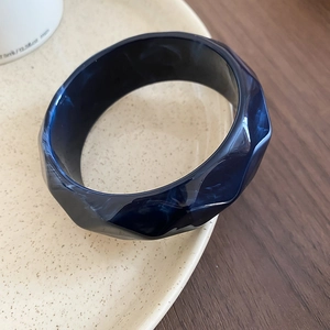 Detailed macro view of deep blue marble pattern acrylic bangle with geometric multi-faceted cut