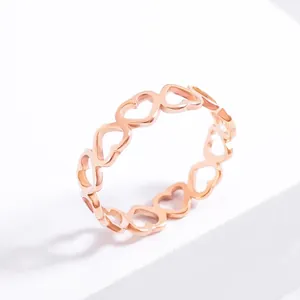 Minimalist rose gold stainless steel ring with hollow heart pattern on white background