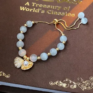 Elegant gold-plated cat eye bead bracelet with pearl shell charm on vintage book surface