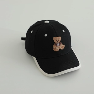 Détail d'une casquette enfant avec broderie ours et panneaux contrastés noir et blanc