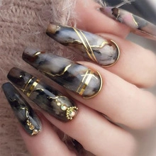 Close-up of long coffin fake nails with dark marble patterns and gold line accents