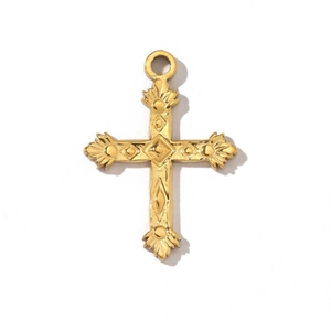 Détail du pendentif croix dorée vintage avec texture en relief finement travaillée