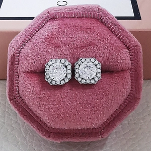 Macro view of white zircon halo stud earrings set in a pink velvet jewelry box
