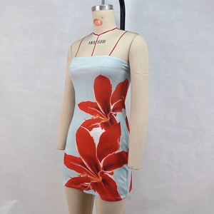 Détail d'une robe courte bleue avec imprimé floral de lys rouges et fines bretelles