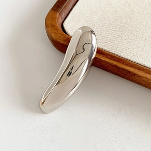 Macro shot of polished silver irregular streamlined metal brooch with a mirror finish