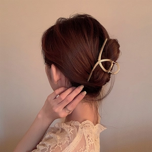 Detail of elegant golden metal shark hair claw clip in a minimalist matte finish