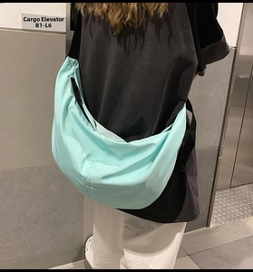 Close-up of mint green nylon crescent bag with adjustable black shoulder strap details