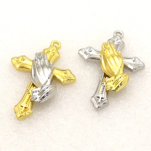 Close-up of dual-tone religious cross pendants with praying hands and ornate scrollwork