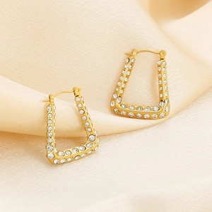 Detail of U-shaped 18K gold-plated titanium earrings with inlaid crystals on beige silk