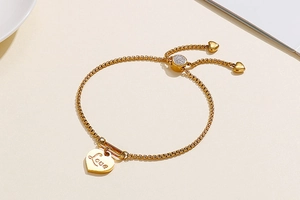 Detail of adjustable gold heart bracelet with Love engraving and shimmering crystals