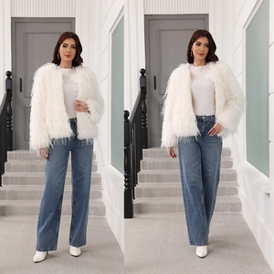 Détail d'un manteau blanc en fausse fourrure avec un jean bleu taille haute et bottes blanches