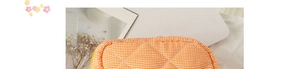 Detail of orange and white gingham quilted makeup bag with soft diamond stitching
