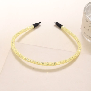 Detailed view of a slim yellow glitter headband with sparkly sequins and black end tips