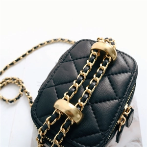 Macro detail of black quilted sheepskin leather bag with gold chain and metal adjusters