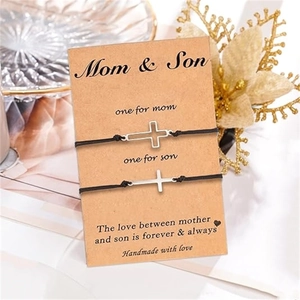Détail de bracelets mère et fils en corde tressée avec croix argentées sur carte